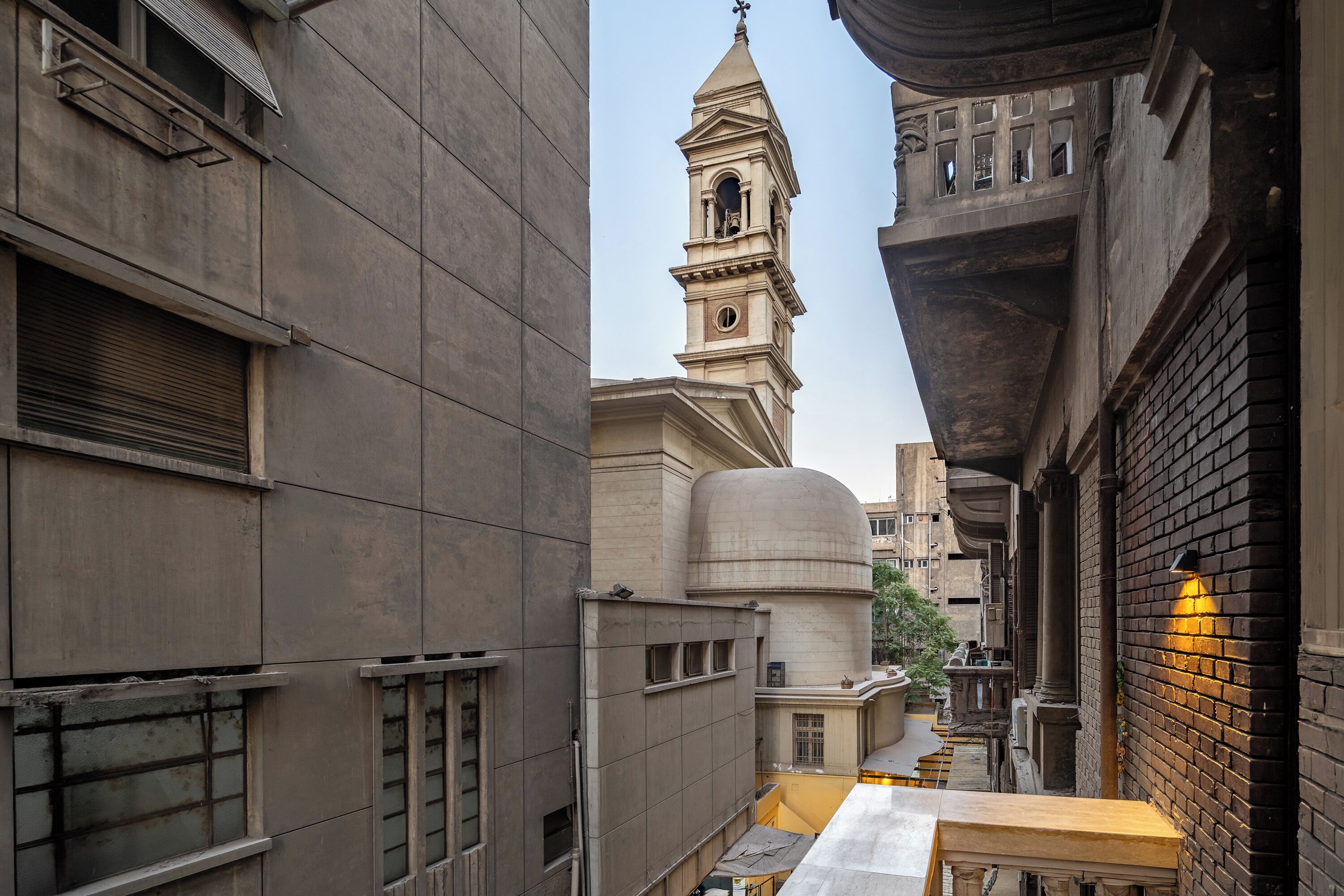 Une rue étroite en milieu urbain, bordée d’un bâtiment historique doté d’un clocher et d’un dôme.