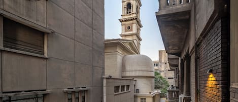 A narrow urban street with a historic building featuring a bell tower and a dome.