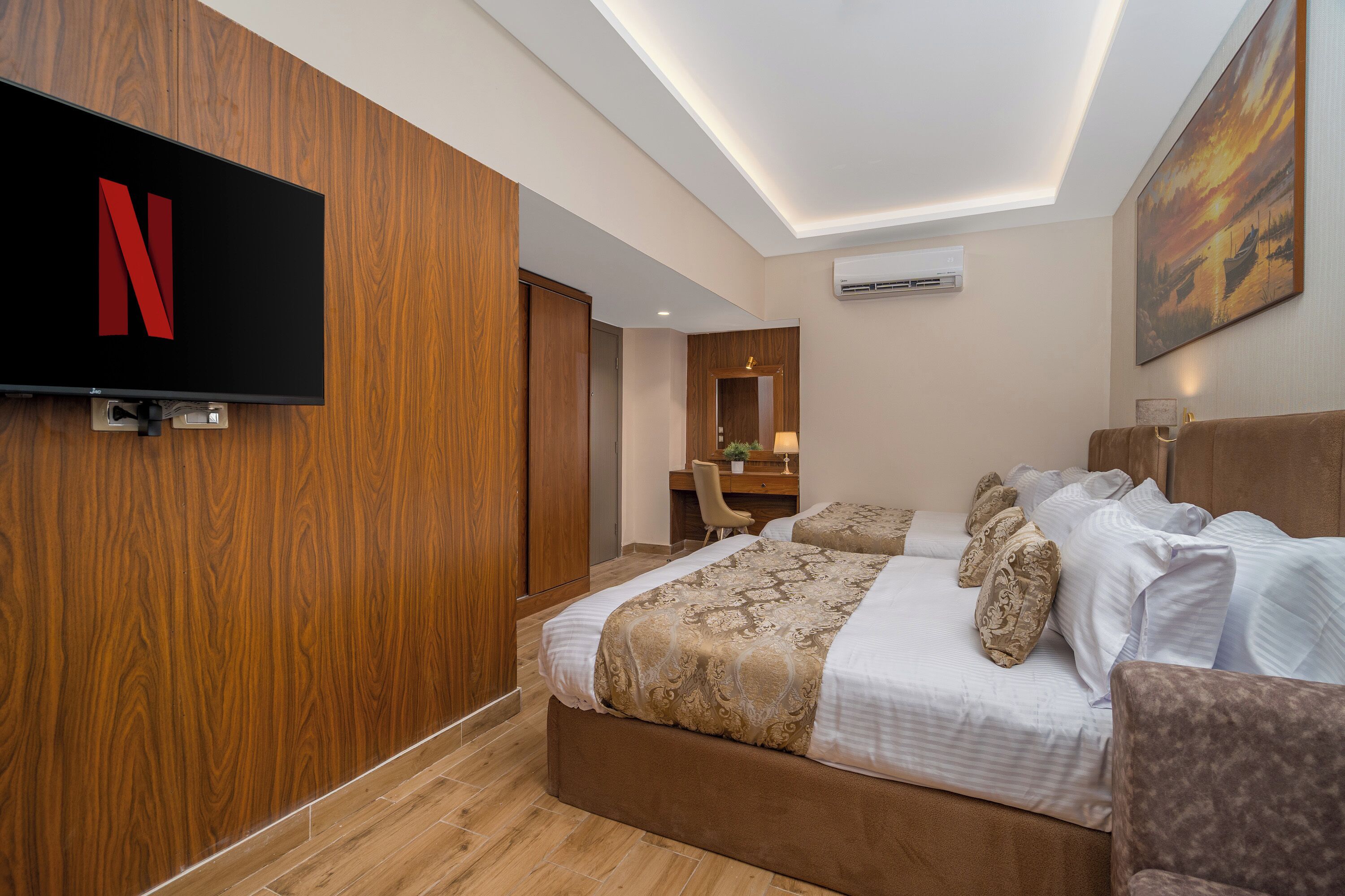 Quarto de hotel com uma cama grande, uma escrivaninha com cadeira, televisão fixada na parede e ar condicionado.