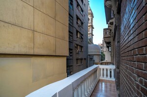 A narrow alleyway between buildings with a white balustrade and a brick wall.