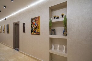 A hallway with artwork on the walls, a door, and a shelf with decorative items.