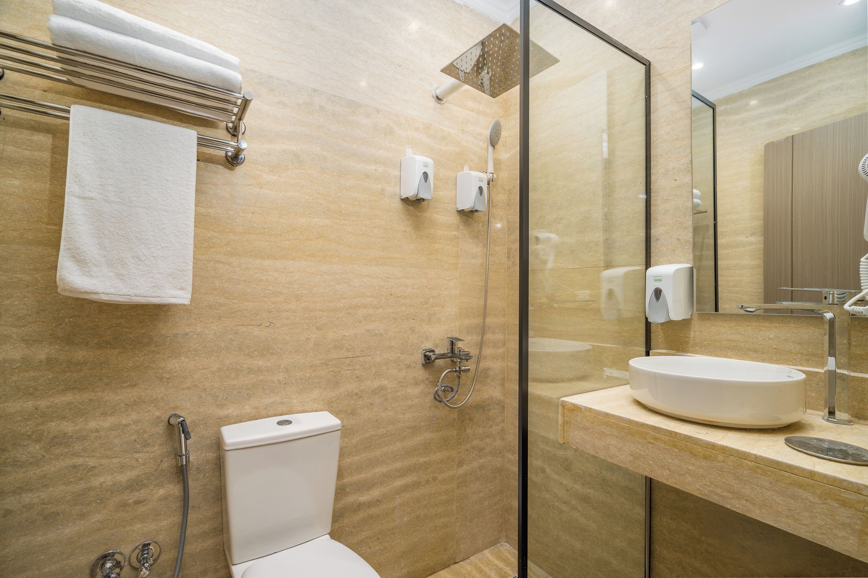 A modern bathroom with a glass shower enclosure, a white toilet, and a round sink with a mirror above it.