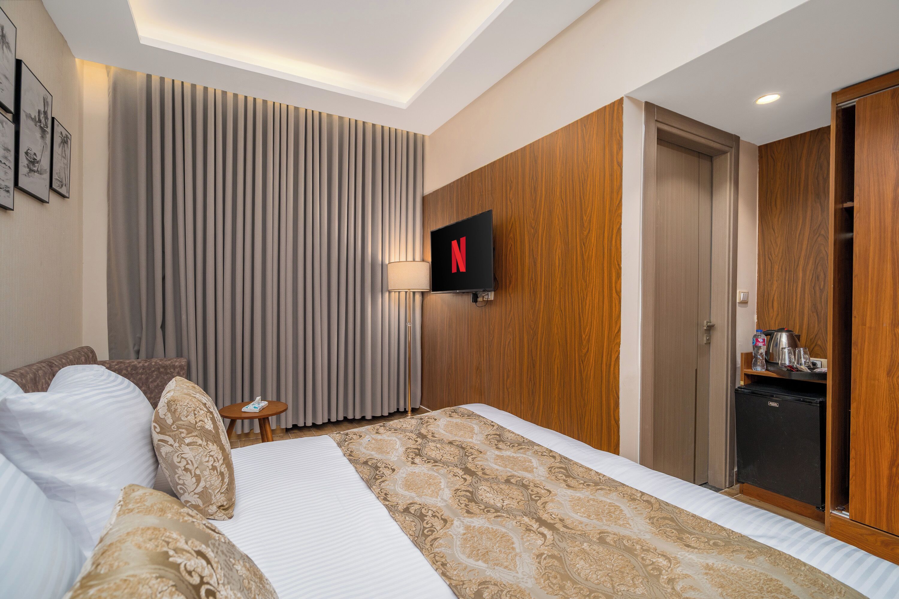 A hotel room with a bed, a television, a desk, and a wardrobe.