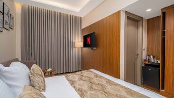 Habitació d'hotel amb un llit, una televisió, un escriptori i un armari.
