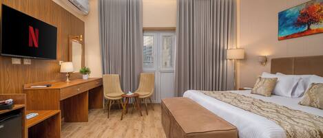Une chambre d’hôtel avec un lit, un bureau, une chaise, une télévision et un tableau au mur.