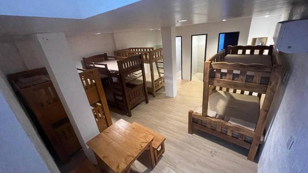 Una habitación con literas, una mesa de madera y un armario.