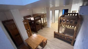 Una habitación con literas, una mesa de madera y un armario.