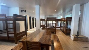Ein Hotelzimmer mit Etagenbetten, einem Holztisch und einer Kiste auf dem Boden.