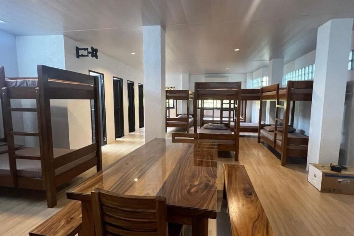 A hotel room with bunk beds, a wooden dining table, and a box on the floor.