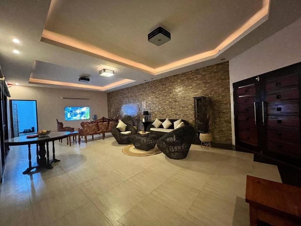 Un saló modern amb una paret d'accent de pedra, un televisor de pantalla plana i una zona de menjador amb taula i cadires.
