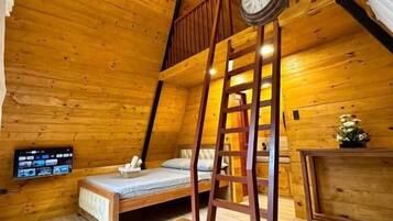 Una habitación acogedora de madera con cama en altillo, una escalera de madera, una mesa de madera y un reloj en la pared.