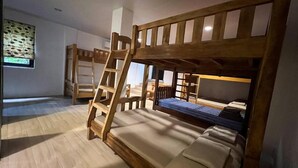 Ein Schlafraum mit Etagenbett, einer kleinen Tisch und einem Fenster mit Jalousien.