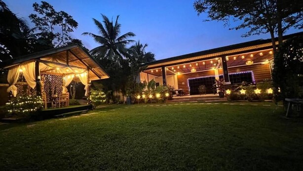 A well-lit outdoor area with a covered seating area and a building with a porch. - CD NatureView (Silang)