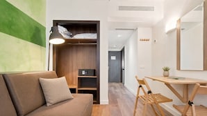 Quarto moderno com sofá, escrivaninha e armário.