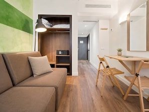 Ein modernes Zimmer mit einer Couch, einem Schreibtisch und einem Kleiderschrank.