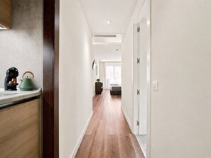 A hallway with a wooden floor, white walls, and a kitchen area with a kettle and coffee maker. - Studio apartment for 4 people near Retiro and Serrano (Madrid)