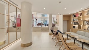 Um interior moderno com uma coluna central, área de estar e uma estante de livros.