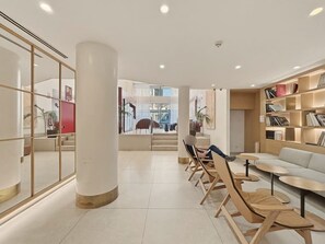 Ein modernes Interieur mit einer zentralen Säule, einer Sitzecke und einem Bücherregal.