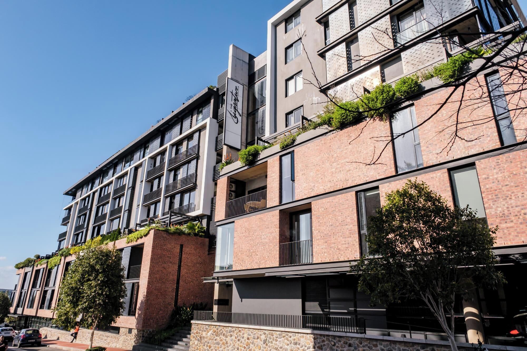 Un immeuble résidentiel à plusieurs étages, doté de balcons et d’une façade en pierre, avec un ciel dégagé.