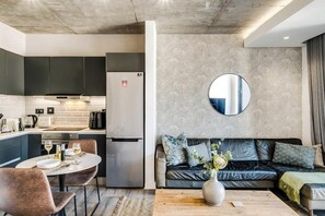 A modern kitchen with a refrigerator, dining table, and chairs. - Mountain View De Waterkant 1 Bed Urban Vue (Cape Town)