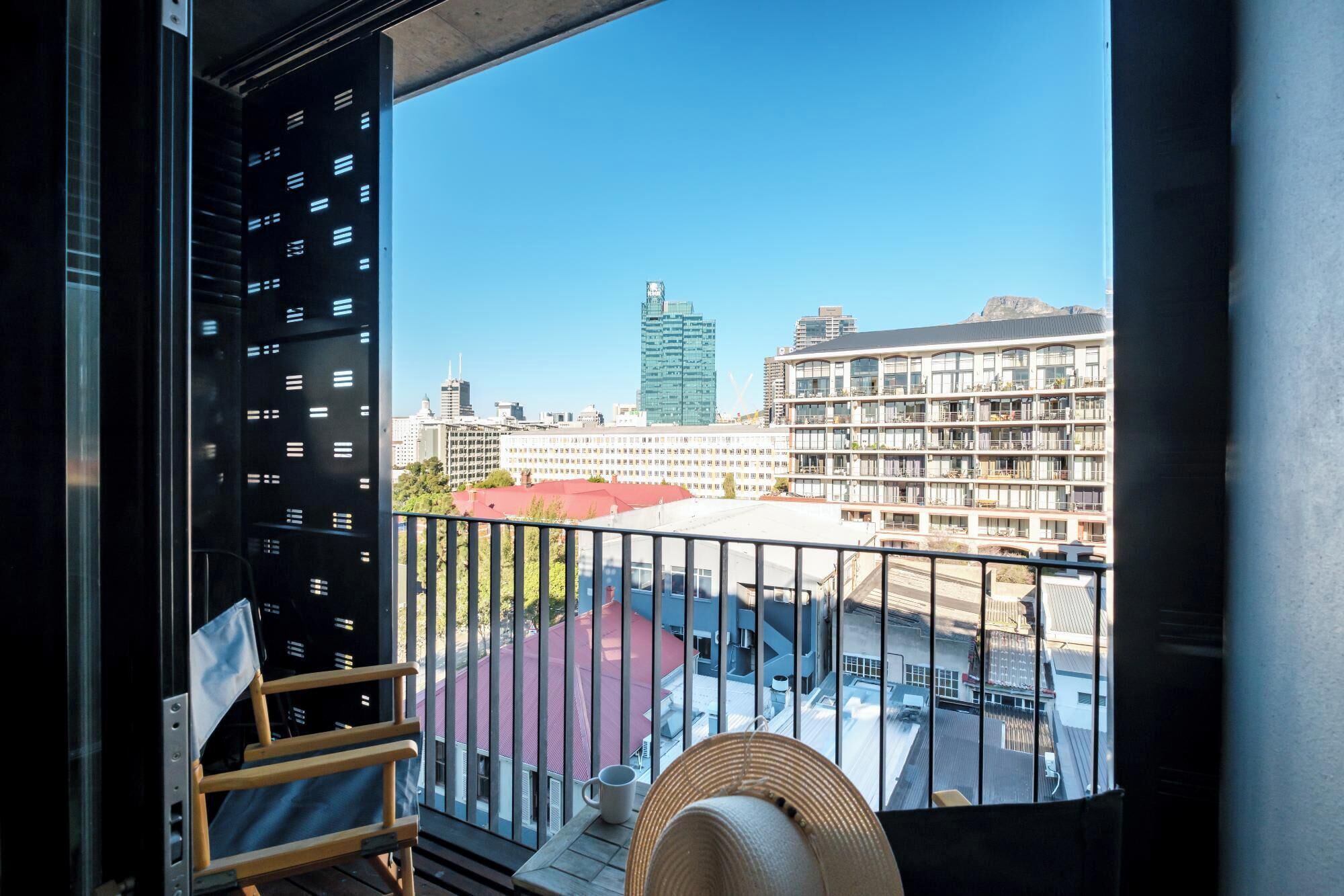 Un balcon offrant une vue sur le paysage urbain, avec notamment un immeuble de grande hauteur et un immeuble résidentiel à plusieurs étages.