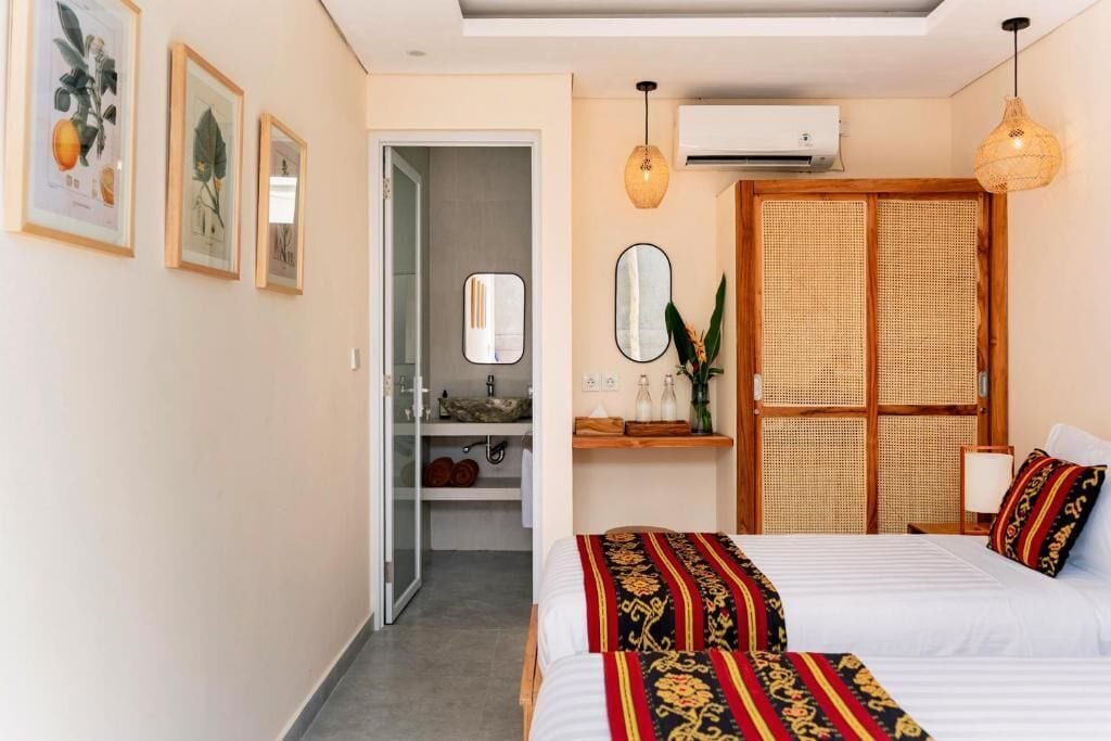 A hotel room with a bed, bedside tables, a mirror, a wardrobe, and a door leading to a bathroom.