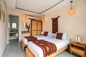 A hotel room with two beds, a bathroom, and a small sitting area. - Ayurveda Hub (Ubud)