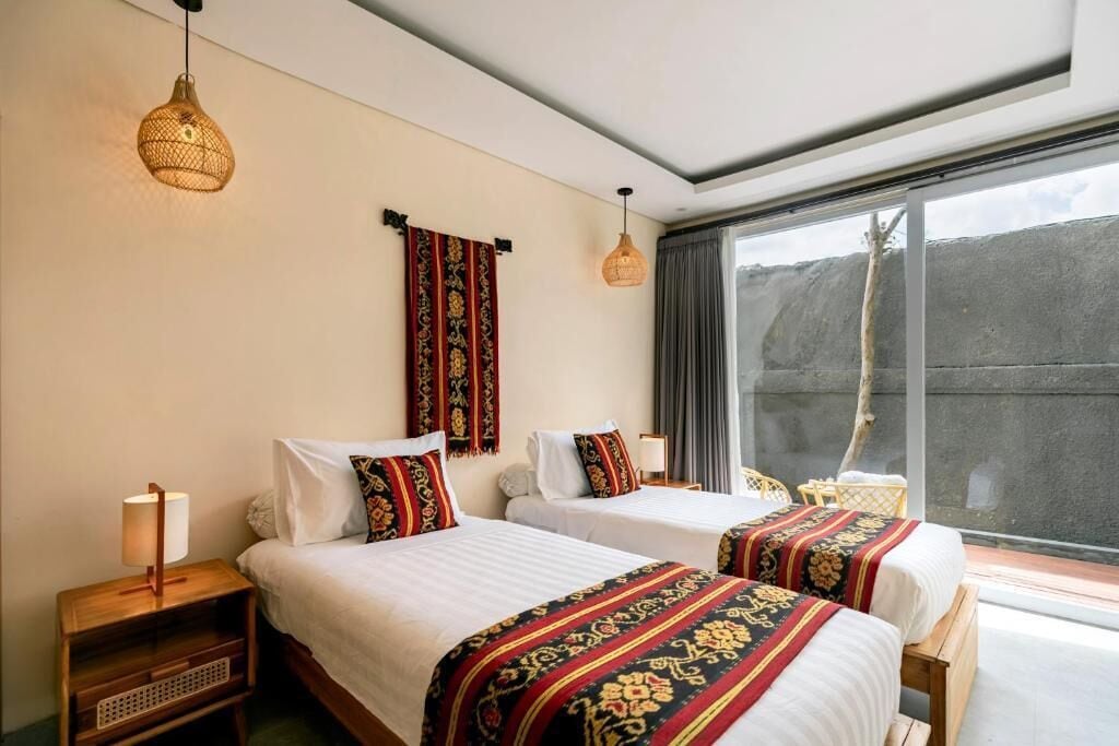 Una habitación de hotel con dos camas, una ventana con vistas y una lámpara colgante.