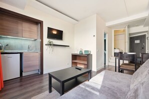 Ein modernes Wohnzimmer mit einer Couch, einem Couchtisch und einem an der Wand befestigten Fernseher.