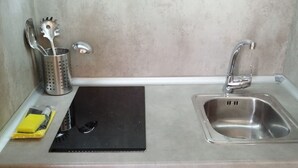 Et køkken med en rustfri stålvask, en sort skærebræt, en gul svamp og en metalkøkkenholder.