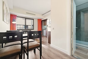 A dining area with a table and chairs, a kitchen in the background, and a sliding glass door leading to a balcony. - Comfort and functionality right next to the Retiro Park (Madrid)