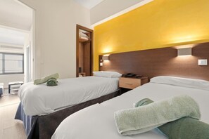 A hotel room with two beds, a wooden headboard, a bedside table with a phone, and a window with a view. - Comfort and functionality right next to the Retiro Park (Madrid)