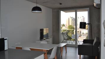 Un espacio habitable moderno con comedor, televisor de pantalla plana y balcón con vistas a la ciudad.