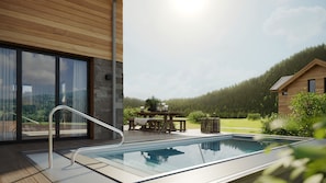 Ein moderner Außenpool mit Glasbarriere, einer Holzterrasse und einer Steinmauer.