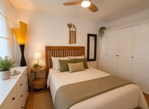 A bedroom with a bed, bedside tables, a ceiling fan, a mirror, and a wardrobe. - Terrasol Berlin 2 in Torre del Mar (Velez-Malaga)
