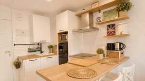 Une cuisine moderne avec des meubles blancs, un îlot central en bois et un bar pour prendre le petit-déjeuner avec des chaises blanches.
