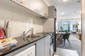 A modern kitchen with a dishwasher, sink, and a dining area with a table and chairs.
