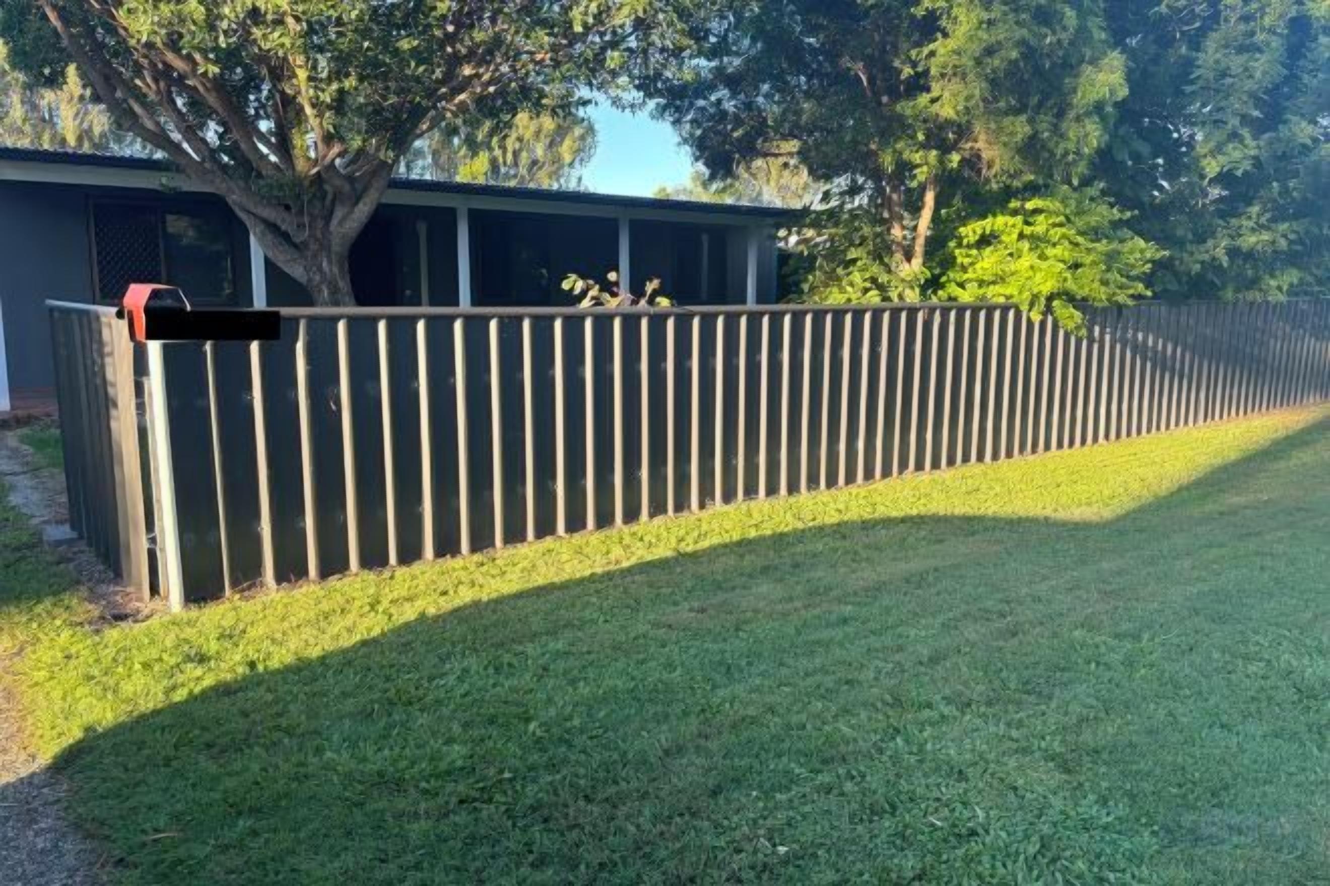 A fenced yard with a grassy area and a building in the background.
