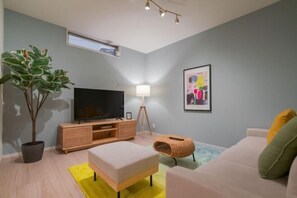 A modern living room with a television, a potted plant, a sofa, and a lamp.