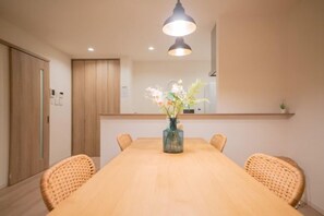 A conference room with a long table, chairs, a vase with flowers, and a pendant light. - Travel Time - Senbon Naka (Osaka)