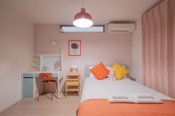 A bedroom with a bed, desk, chair, and a window.
