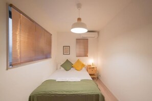 A bedroom with a bed, bedside table, lamp, and window blinds. - Travel Time - Senbon Naka (Osaka)