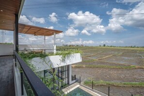 Un edifici modern amb un balcó que dona a un camp de conreu d'arròs.