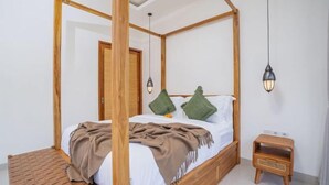 A four-poster bed with a wooden frame, a bedside table, and a hanging lamp.