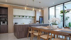 A modern kitchen with wooden cabinetry, a central island, and pendant lighting.