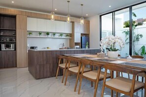 A modern kitchen with wooden cabinetry, a central island, and pendant lighting.