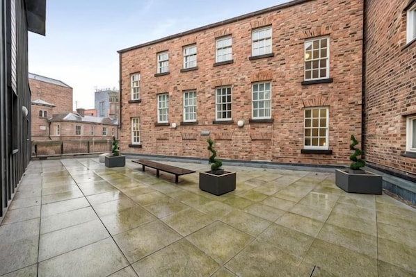 A courtyard with a brick building, a bench, and planters.