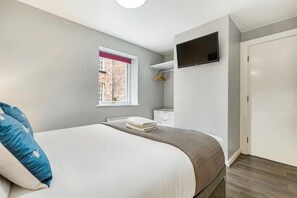 A bedroom with a bed, a window, a television, and a wardrobe.