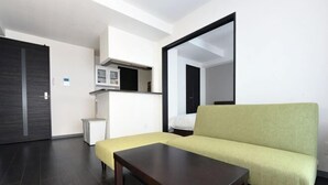 Una sala de estar moderna con un sofá, una mesa de centro, un microondas y un mueble pequeño.
