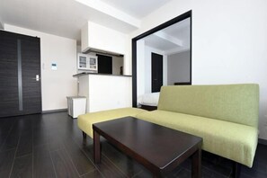 A modern living room with a sofa, a coffee table, a microwave, and a small cabinet.